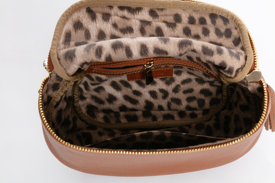 Leopard print interior of 3 interior compartments including a small zippered compartment with a gold zipper on a white background